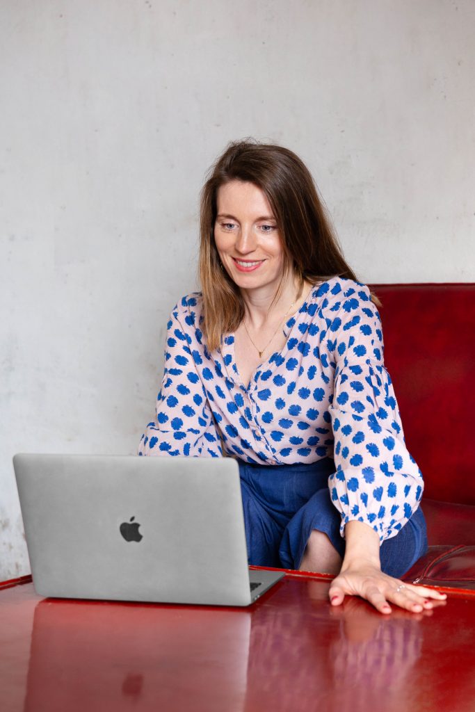 Grafikdesignerin sitzt am Arbeitsplatz vor dem Laptop und bearbeitet Emails