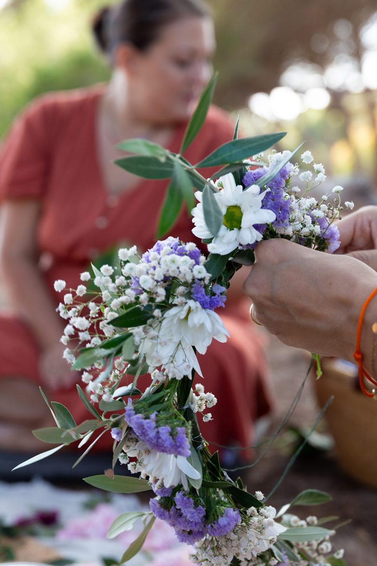 Gebundener Blumenkranz für die Blessingway-Zeremonie mit Doula im Hintergrund